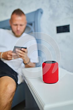 Male testing talking smart wireless speaker, man controlling home devices with a voice commands
