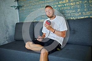 Male testing talking smart wireless speaker, man controlling home devices with a voice commands