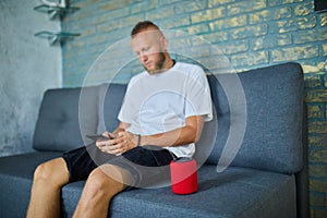 Male testing talking smart wireless speaker, man controlling home devices with a voice commands