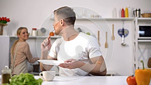 Male thanking female for delicious meal, wife smiling on background in kitchen