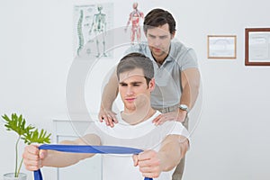 Male therapist assisting man with exercises in office