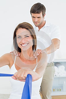 Male therapist assisting young woman with exercises