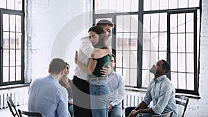 Male therapist embracing female patient giving support during group therapy