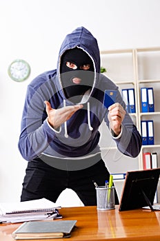 Male thief in balaclava in the office