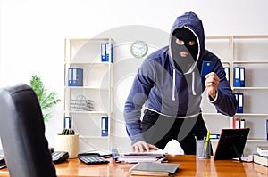 Male thief in balaclava in the office