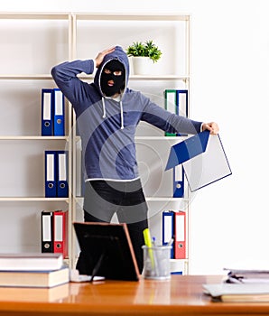 Male thief in balaclava in the office