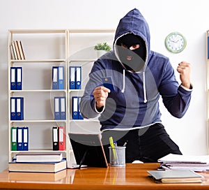 Male thief in balaclava in the office