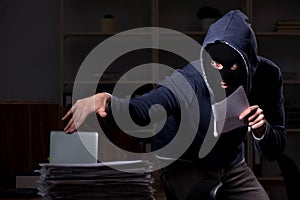 Male thief in balaclava in the office night time