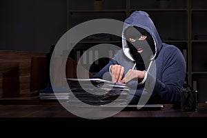 Male thief in balaclava in the office night time