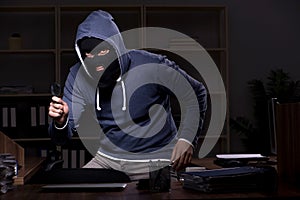 Male thief in balaclava in the office night time