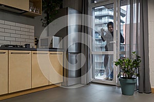 Male thief in black clothes trying to break the door lock in the house