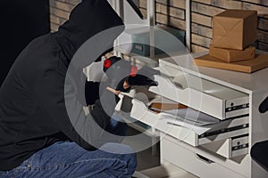 Male thief with flashlight  searching for documents in office