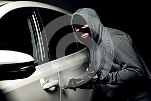 Male thief is going to open the car door with a crowbar