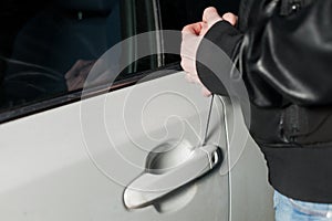 Male thief hands open car door with screwdriver