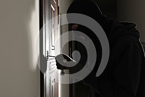 Male thief opening door with keys indoors