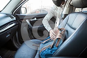 Male thief stealing bag through the opened door of car, man dressed black facemask