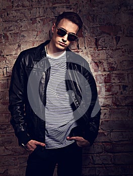 Male thinking model posing in leather jacket and trendy eyeglass