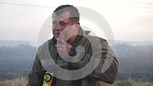 Male tired firefighter wiping away the water on his face after hard work. Portrait of young fireguard in uniform after