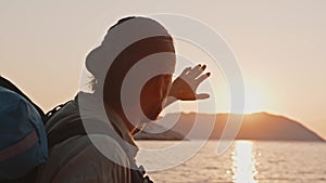 Male tourist with a backpack meets the sunrise by the sea on the island