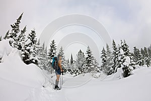 Male tourist with a backpack, with a naked torso and legs is among the snowdrifts and trees
