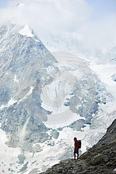Male tourist climbing snowy rocky cliffs of beautiful Penning Alps in Switzerland
