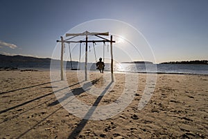 Male tourist enjoys sunset view on a swing