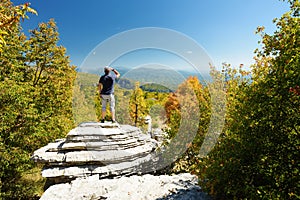 Male tourist exploring Stone forest, natural rock formation, created by multiple layers of stone, located near Monodendri village