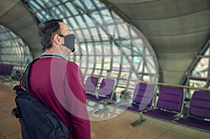 Male tourist in face mask checks the interior design of airport