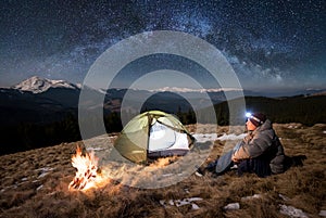 Male tourist have a rest in his camp at night under beautiful sky full of stars and milky way