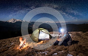 Male tourist have a rest in his camp at night under beautiful sky full of stars and milky way photo