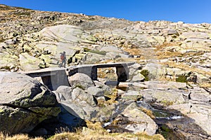 Male tourist hiking on stone bridge, trail to the Laguna Grande de Gredos lake, Spain photo