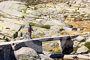 Male tourist hiking on stone bridge, trail to the Laguna Grande de Gredos, Spain. photo
