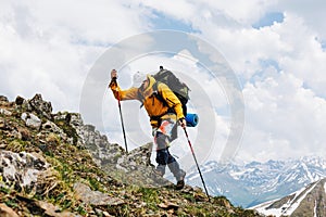 Male tourist with a large backpack and mountain poles climbs