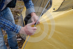 Male tourist making a tent at forest camp.