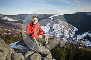 Male tourist sitting on rock on top of the mountain