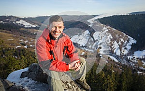 Male tourist sitting on rock on top of the mountain