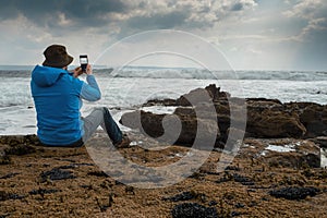 Male tourist standing on a rough stone coast. Aran island, county Galway, Ireland. Blue cloudy sky in the background. Travel and