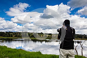 Male tourist taking photos at an artificial lake in the region of Boyaca in Colombia. La Playa reservoir located at the Tuta