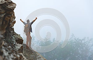 Male tourist on top of mountain in fog in autumn