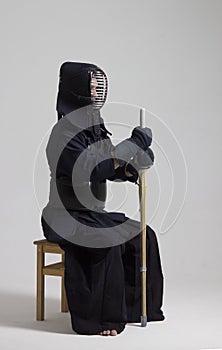 Male in tradition kendo armor with shinai bamboo sword .