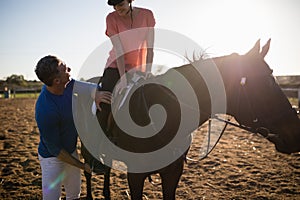 Male trainer adjusting young woman leg on stirrup