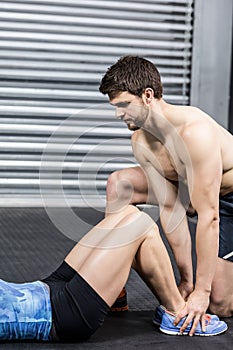 Male trainer assisting woman with sit ups