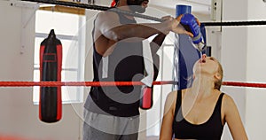 Male trainer feeding water to female boxer in boxing ring 4k