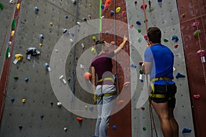 Male trainer guiding woman in climbing wall at club