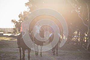 Male trainer guiding women in riding horse