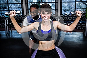 Male trainer helping woman during dumbbells exercise