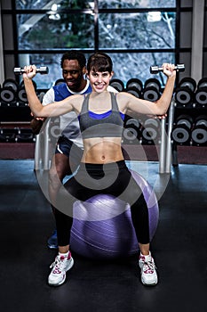 Male trainer helping woman during dumbbells exercise