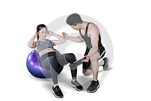 Male trainer helping young woman doing workout