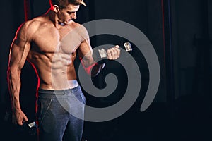 Male trainer with muscular torso holding dumbbells in hands at cross fit gym