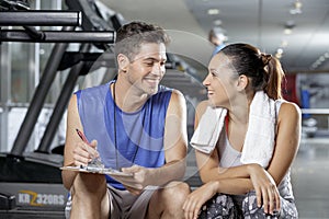 Male trainer sitting in gym with client
